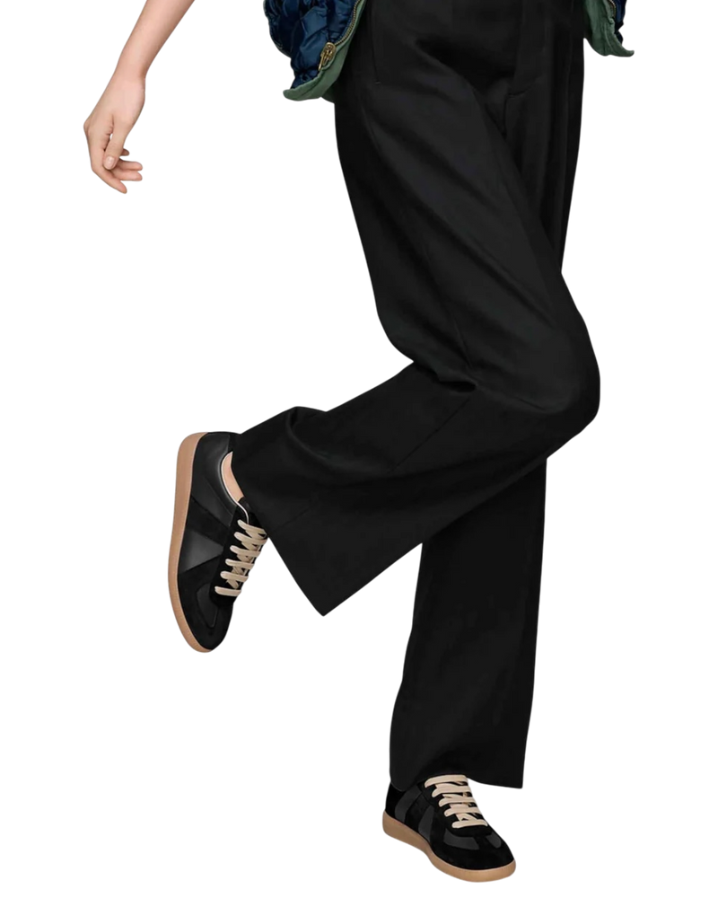 Maison Margiela Replica German Army Trainer in black and gum on model, worn with wide black trousers mid-stride