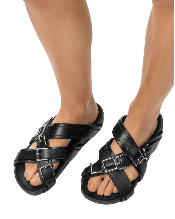 Loewe Type Fussbett sandal in black on model, front view of the pair with crisscross leather straps and silver buckles