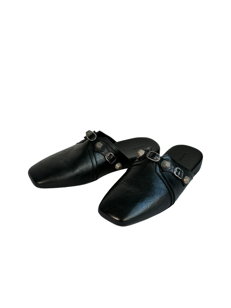 Balenciaga Cosy Cagole mules in black leather, angled view of the pair with studs and buckled crossover straps