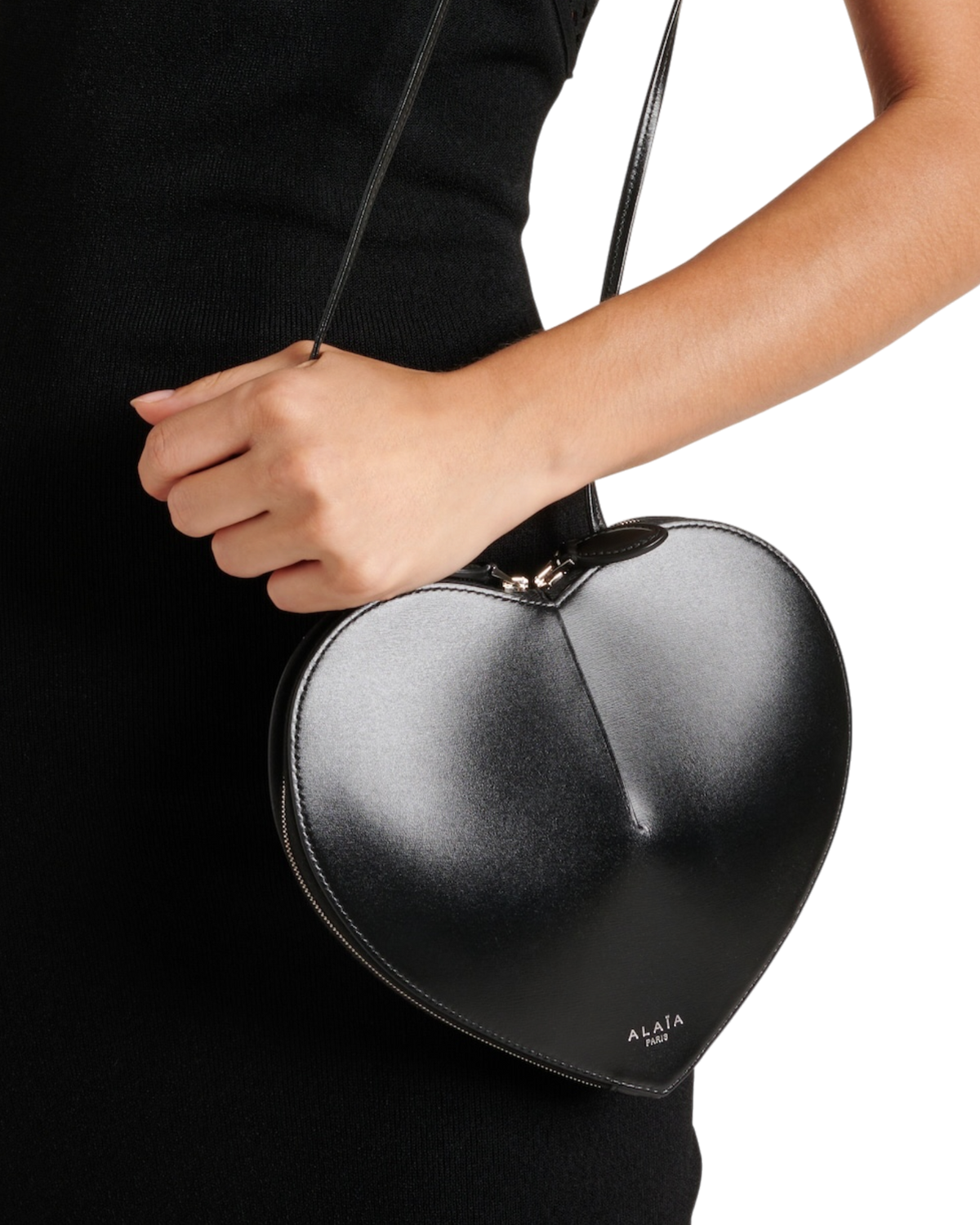 Alaïa Le Coeur leather shoulder bag in black on model, close-up of the sculpted heart shape held by its slim strap