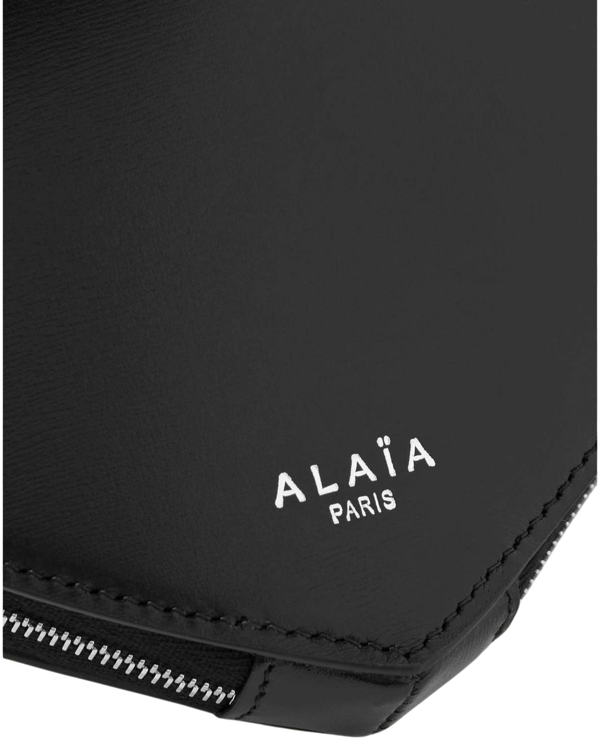 Alaïa Le Coeur leather shoulder bag in black, detail close-up of the white Alaïa Paris logo and zipper edge