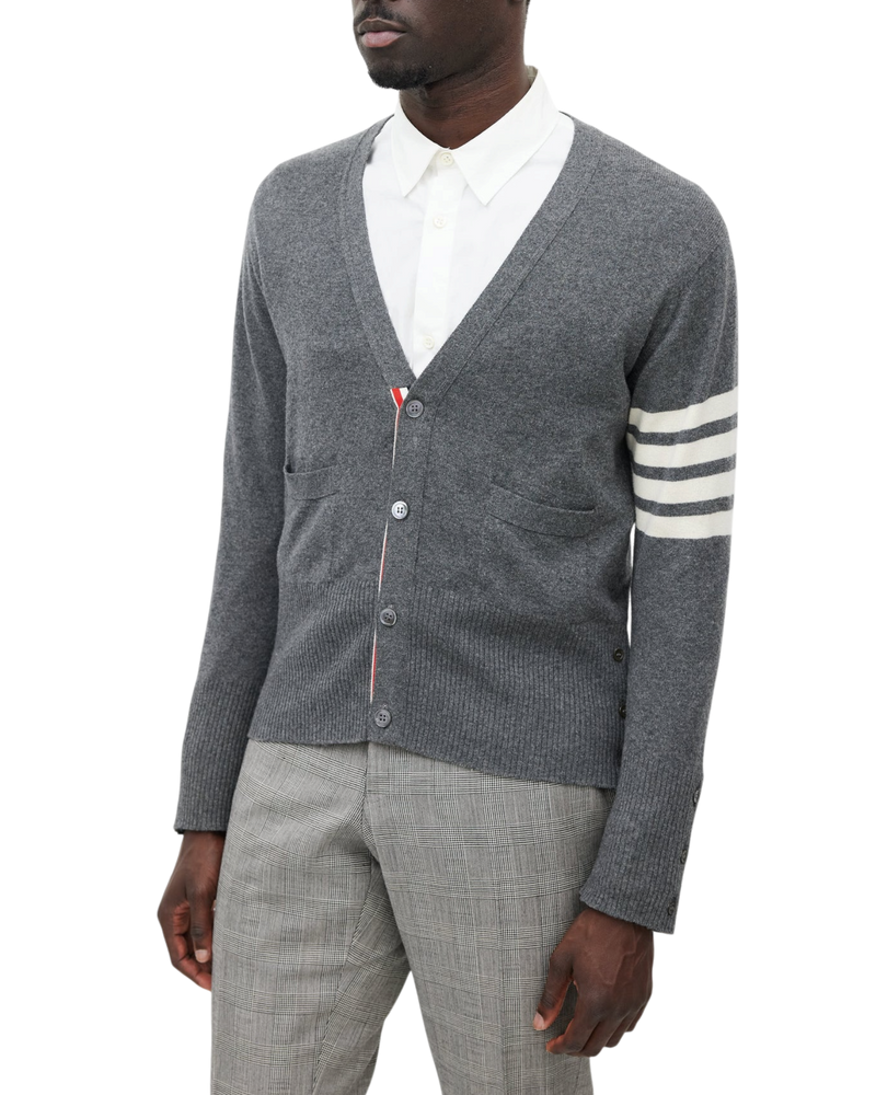 Thom Browne cashmere cardigan in grey on model, V-neck front with patch pockets and white four-bar sleeve stripes