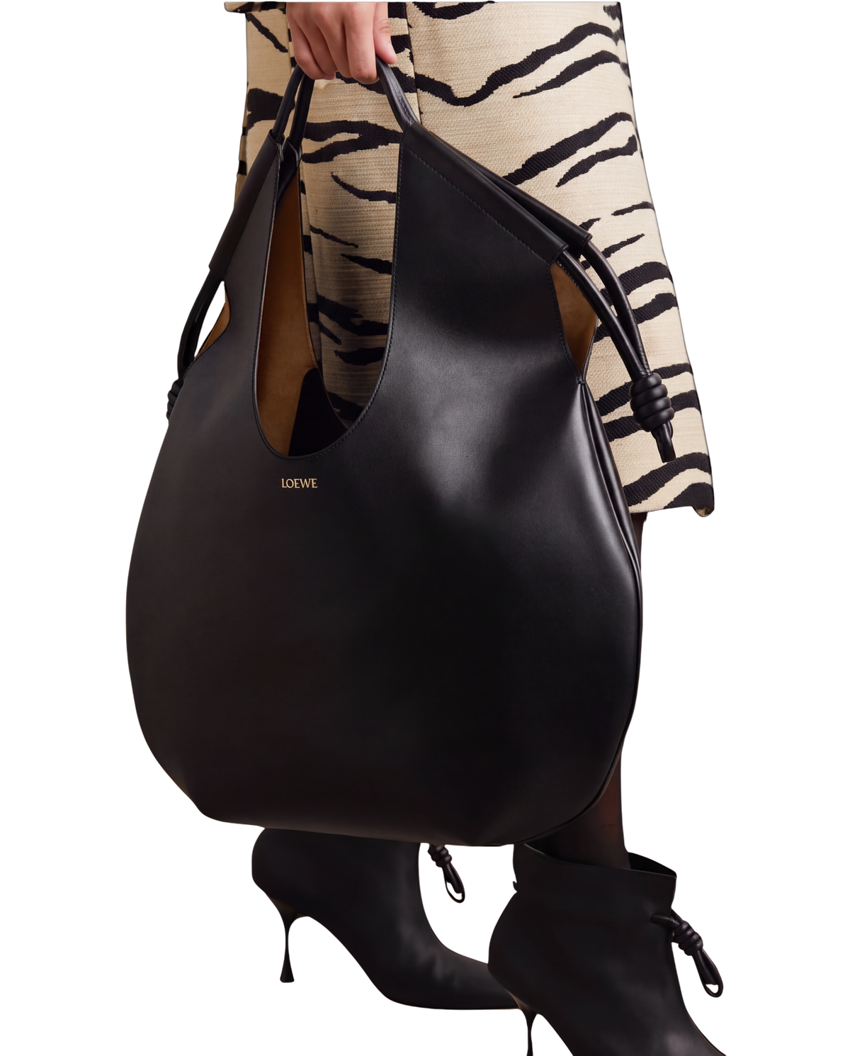 Loewe Paseo knotted leather tote in black on model, carried by the top handle with knotted cord ends at each side