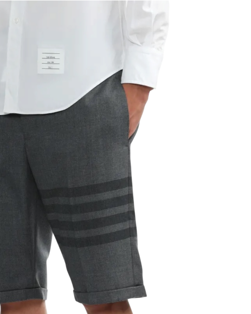 Thom Browne 4-Bar shorts in grey on model, side view with tonal charcoal stripes on the leg and cuffed hem