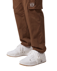 Loewe deconstructed sneakers in soft white denim on model, side view of the pair with oversized laces and gum-edge soles