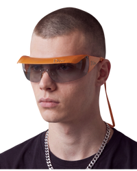 Dior Golf shield sunglasses in orange on model, worn with the clip-on Dior visor and orange eyewear cord