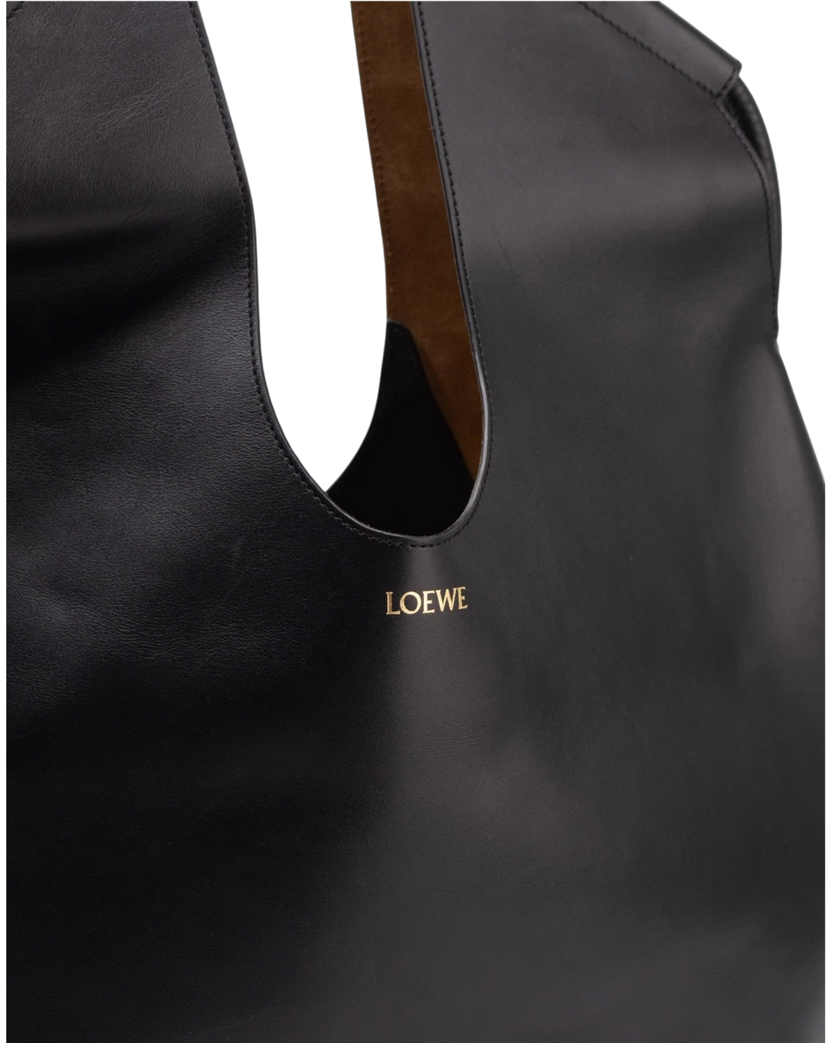 Detail of the gold-stamped LOEWE house mark on the front of the black leather tote, beside the tan suede handle lining