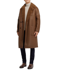 Full-length styling shot with the brown Chelsea boots worn under dark denim and a shearling coat